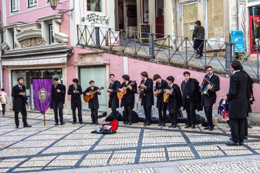 Coimbra, Portekiz - 15 Aralık 2024: Portekiz 'deki Coimbra Üniversitesi öğrencileri şehrin tarihi sokaklarında geleneksel müzik çalıp söylüyorlar