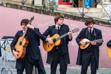 Coimbra, Portekiz - Mar 02, 2025: Portekiz 'deki Coimbra Üniversitesi öğrencileri şehrin tarihi sokaklarında geleneksel müzik çalıp söylüyorlar