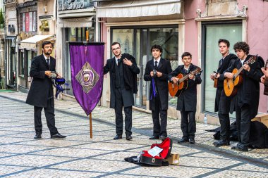 Coimbra, Portekiz - 15 Aralık 2025: Portekiz 'deki Coimbra Üniversitesi öğrencileri şehrin tarihi sokaklarında geleneksel müzik çalıp söylüyorlar
