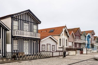 Renkli evleri olan bir sokak. Çizgili evleri olan cadde, Costa Nova, Aveiro, Portekiz. Kosta Nova, Aveiro, Portekiz 'deki renkli evlerin cepheleri.