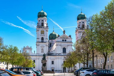 Passau, Almanya - 16 Nisan 2025: Passau, Almanya 'daki St. Stephans Katedrali kulelerin tepesinde yeşil metal kubbeler bulunan eski bir beyaz kilisedir. Kilisenin önünde Maximillian Joseph 'in heykeli var.