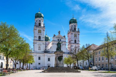 Passau, Almanya - 16 Nisan 2025: Passau, Almanya 'daki St. Stephans Katedrali kulelerin tepesinde yeşil metal kubbeler bulunan eski bir beyaz kilisedir. Kilisenin önünde Maximillian Joseph 'in heykeli var.