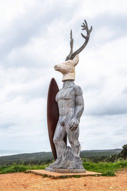 Nazare, Portekiz - Mar 08, 2025: Geyik başlı bir sörfçü, 6 metre yüksekliğinde, Portekiz 'in Avrupa kentindeki Nazare deniz feneri yoluna kurulmuş.