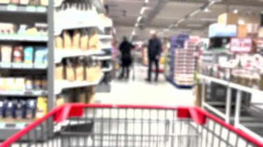 Bulanık satış rafları ve süpermarketten alışveriş yapan insanlar.