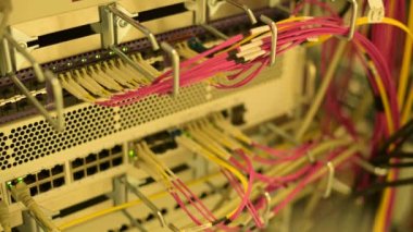 Bir veri merkezinde RJ45 ve fiber optik kablo bağlantıları olan bir sunucu rafında yanıp sönen LED ışıkları