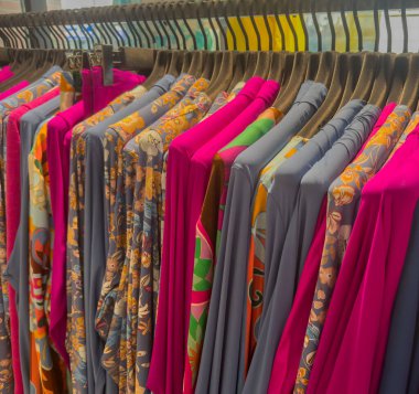 Bir mağazadaki elbise rafında renkli gömlekler ve bluzlar.