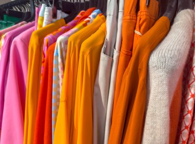Bir mağazadaki elbise rafında renkli gömlekler ve bluzlar.