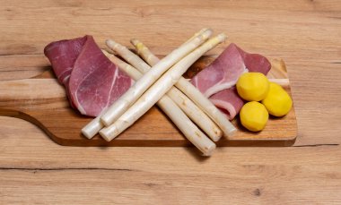 Tahta tabakta taze jambon ve patates ile beyaz kuşkonmaz.