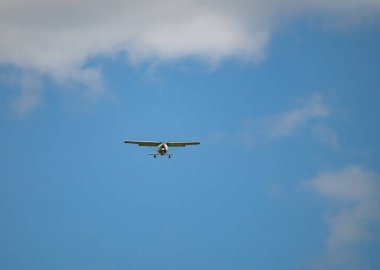 Tek motorlu uçak. Mavi gökyüzüne ve beyaz bulutlara karşı havada hafif bir uçak.