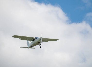 Tek motorlu uçak. Mavi gökyüzüne ve beyaz bulutlara karşı havada hafif bir uçak.