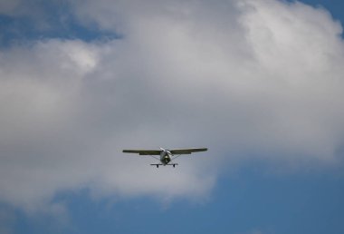 Tek motorlu uçak. Mavi gökyüzüne ve beyaz bulutlara karşı havada hafif bir uçak.