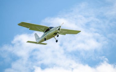 Tek motorlu uçak. Mavi gökyüzüne ve beyaz bulutlara karşı havada hafif bir uçak.