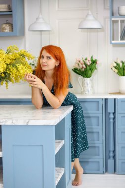 Mutfakta neşeli bir kız var. Bir buket sarı mimoza.