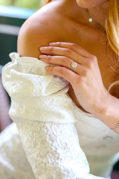 A woman\'s hand at the shoulder close up. Girl in a white dress. Bride. Greenery and summer background. Sexuality concept