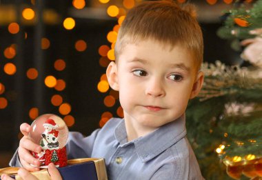 Sevimli çocuk elinde Noel Baba 'yla balona bakıyor. Mavi gömlekli ve kot pantolonlu, yeni yıl arifesi. Peri masalı ve tatil konsepti