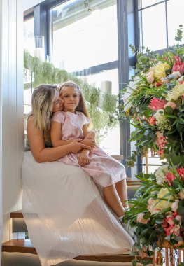 Evlerindeki merdivenlerde otururken kızını kollarında tutan şefkatli bir anne. Aile ve aşk kavramı.