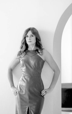 Şık, esmer ve kıvırcık saçlı bir kızın siyah beyaz fotoğrafı. Kemerli parlak bir iç mekan. Moda ve güzellik konsepti