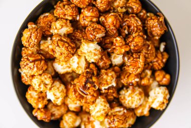 Sweet ready-to-eat popcorn in a black ceramic plate close up.