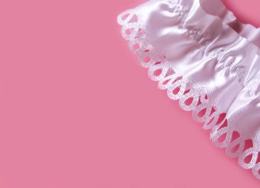 The bride's garter on a pink background. Wedding dress detail.
