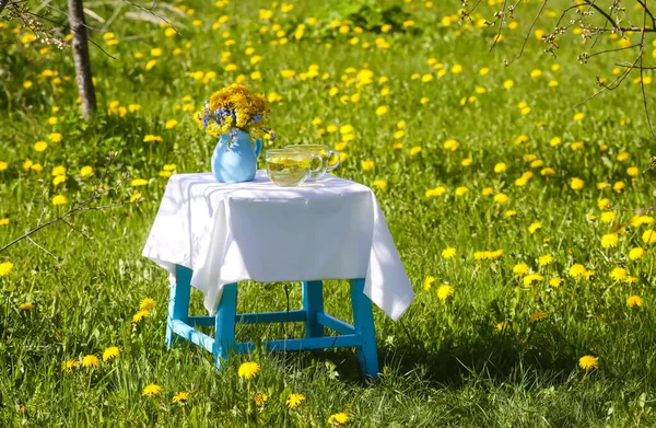 Herbal tea on a small table with floral decor outdoors.