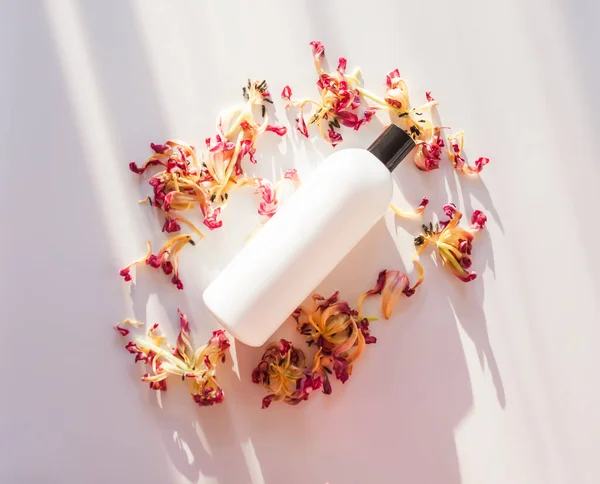 Etrafında Kurumuş Çiçek Yaprakları Olan Beyaz Markasız Plastik Bir Şişe — Stok fotoğraf