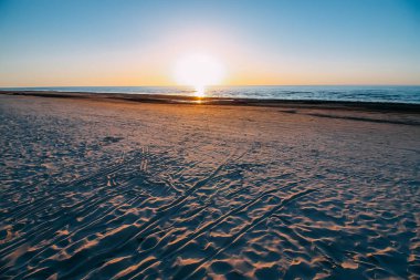 Gün batımında Baltık Denizi. Kumsalda sıcak, altın bir akşam ışığında.
