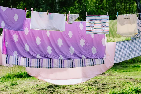 ロープに掛かる洗濯されたカラフルなコットンランドリー 裏庭で乾燥する織物 — ストック写真