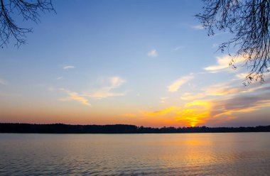 Letonya 'da sonbahar günbatımında gölü olan huzurlu bir manzara.