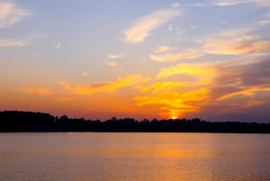 Letonya 'da sonbahar günbatımında gölü olan huzurlu bir manzara.