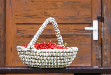 Kırmızı frenk üzümü sepetinde ahşap kapının arkasında köyde..