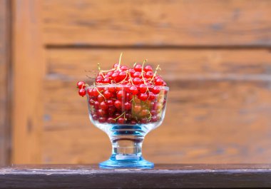 Ahşap duvarda küçük cam bir fincanda üzümlü üzümler..