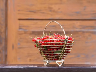 Kırmızı frenk üzümü, ahşap kapılı küçük metal bir sepetin içinde..