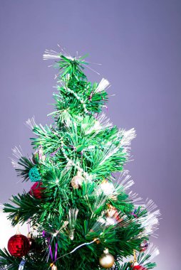 Yapay Noel ağacı, iç dekore edilmiş bir ev içinde mücevher, top ve oyuncaklarla süslenmiş..
