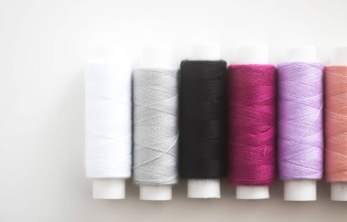 Açık arkaplanda birçok renkli dikiş iplikleri.