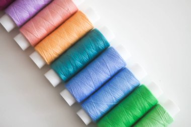 Açık arkaplanda birçok renkli dikiş iplikleri.