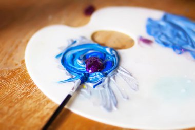 Beyaz plastik bir palette lekelenmiş parlak akrilik boya..