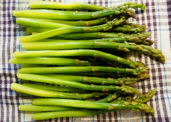 Beyaz bir leylak havlusunda bir sürü haşlanmış yeşil kuşkonmaz vardır. Yüksek kalite fotoğraf