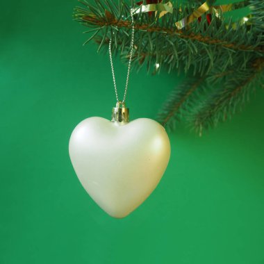 Noel ağacı için süslemeler. Beyaz kalp şeklinde bir Noel oyuncağı yeşil arka plandaki bir Noel ağacının dalında asılı duruyor. Yüksek kalite fotoğraf
