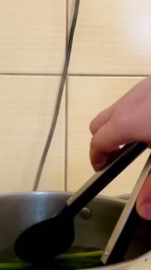 Mutfakta maşayla pişirilmiş yeşil kuşkonmaz sapları çekme işlemi. Sağlıklı yemek. Öğle yemeği için sebze pişiriyorum.