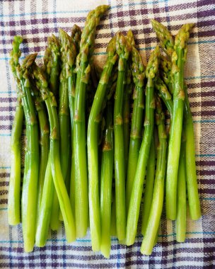 Beyaz bir leylak havlusunda bir sürü haşlanmış yeşil kuşkonmaz vardır. Üst Manzara. Yüksek kalite fotoğraf