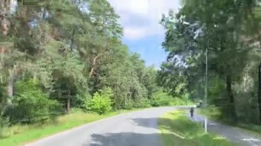 Yeşilliklerle kaplı sessiz bir köy yolu sağa döner. Bu cazip manzara açık hava yaşam tarzı tanıtım materyalleri, seyahat broşürleri veya çevre kampanyaları için idealdir..