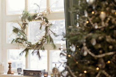 Aydınlık çatı katının penceresinde asılı güzel bir Noel çelengi
