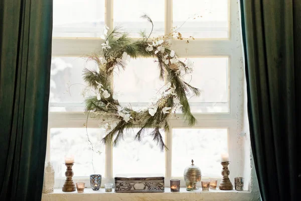 Beautiful Christmas wreath hanging on the window at light loft interior
