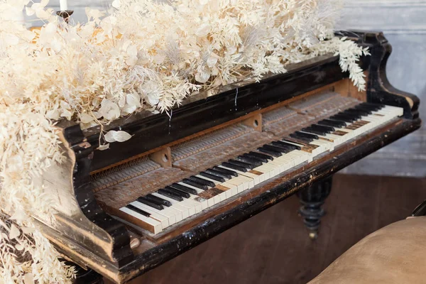 Vintage grand piano with white flowers lunaria and ruscus at light interior