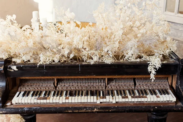 Vintage grand piano with white flowers lunaria and ruscus at light interior