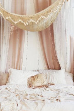 Vintage bohemian bedroom with baldaquin, pillows and blanket