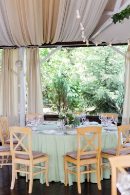 İçerideki bir parti masasında yeşil ve beyaz çiçekli masa düzenleme ve çiçek kompozisyonu. Güzel dekorasyonu olan bir restoran, düğün dekorasyonu konsepti.