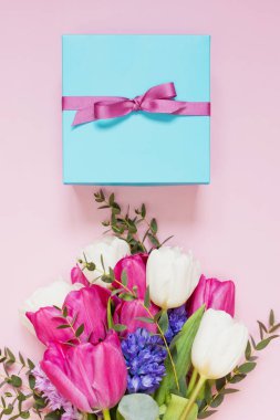 Güzel bir buket ve pembe arka planda kurdeleli mavi hediye kutusu. Fotokopi alanı ile tatil konsepti, metin için yer. 8 Mart, anneler günü teması