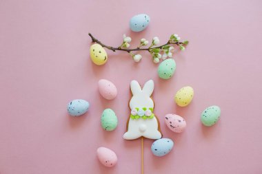 Paskalya kurabiyeleri ve pembe arka planda renkli yumurtalar.