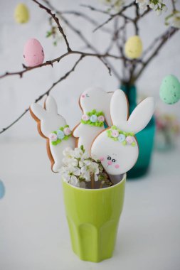 Paskalya kurabiyeleri yeşil vazoda, Paskalya ağacının yanında renkli yumurtalarla.